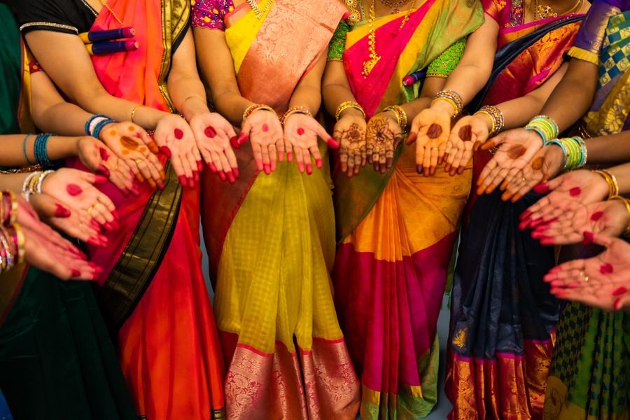 Women in traditional Indian sarees with alta and mehendi